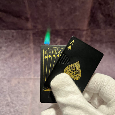 Black Ace Poker Card Torch Lighter – refillable butane lighter shaped like an Ace of Spades card, producing a green-blue torch flame while held in a gloved hand