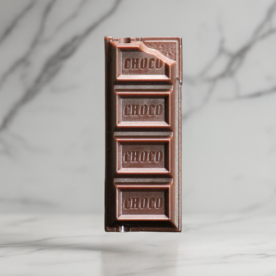 Realistic chocolate bar lighter standing upright, shaped like a chocolate bar with detailed engravings on a marble surface.