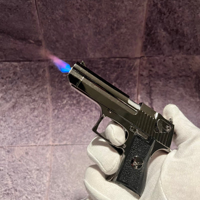 Desert Eagle Lighter – refillable gun-shaped butane lighter with blue torch flame, held in a gloved hand