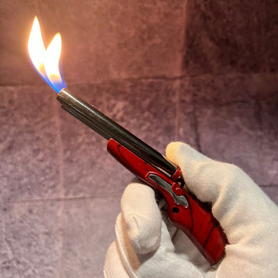 Double Flame Shotgun Lighter – red and silver refillable butane lighter with dual torch flames, held in a gloved hand.