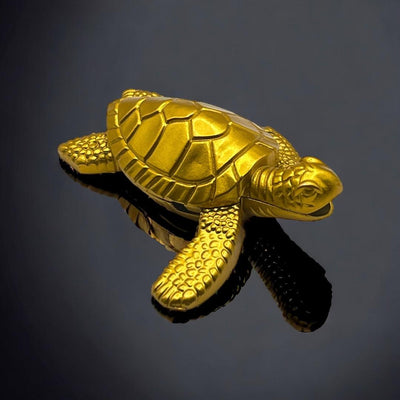 Sea Turtle Lighter – gold refillable butane lighter with detailed turtle shell design, displayed on glossy black reflective surface